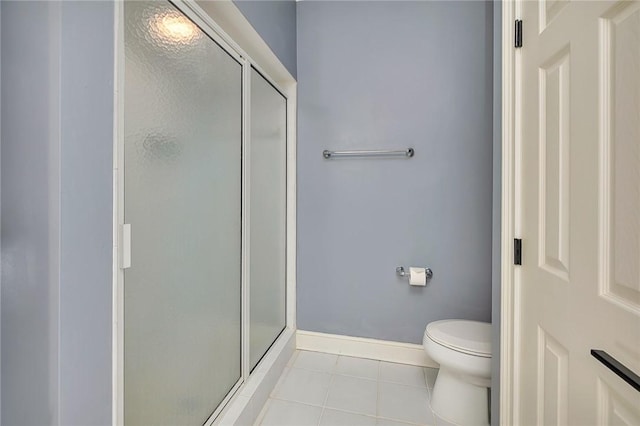 bathroom with tile patterned flooring, a shower with shower door, and toilet