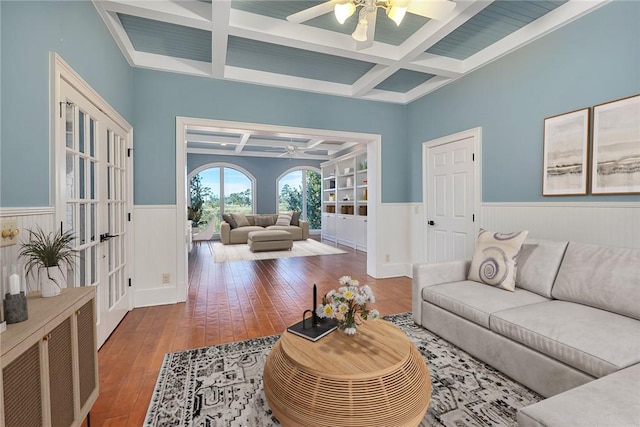 living room with beam ceiling, wood-type flooring, coffered ceiling, and ceiling fan