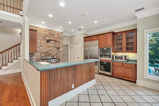 kitchen with sink, decorative backsplash, kitchen peninsula, stainless steel appliances, and crown molding