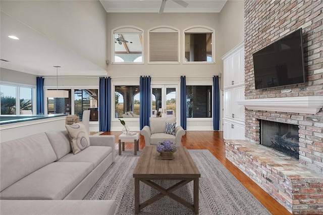 living room with crown molding, wood-type flooring, and a brick fireplace