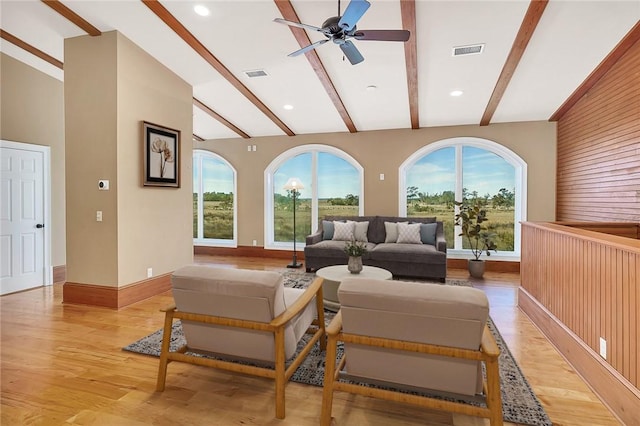 living room featuring lofted ceiling with beams, wood walls, ceiling fan, and light hardwood / wood-style flooring