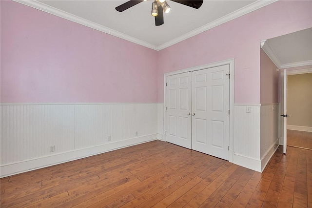 unfurnished bedroom with ceiling fan, ornamental molding, wood-type flooring, and a closet