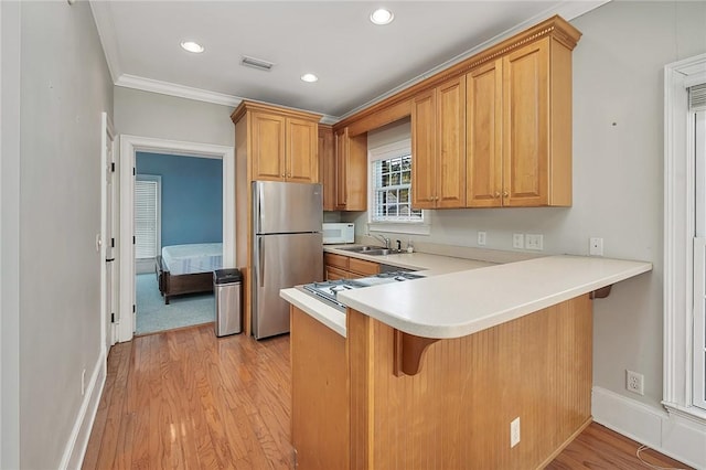 kitchen with sink, stainless steel fridge, light hardwood / wood-style floors, ornamental molding, and kitchen peninsula