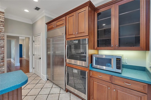 kitchen featuring crown molding, appliances with stainless steel finishes, and light tile patterned floors