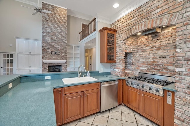 kitchen with sink, light tile patterned floors, stainless steel appliances, a fireplace, and ornamental molding