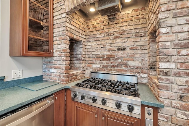 kitchen with wall chimney range hood, stainless steel appliances, and brick wall