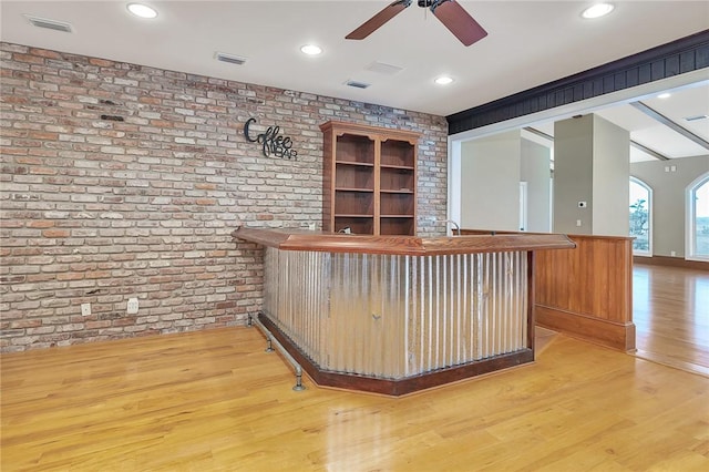 bar featuring light hardwood / wood-style flooring, ceiling fan, and brick wall