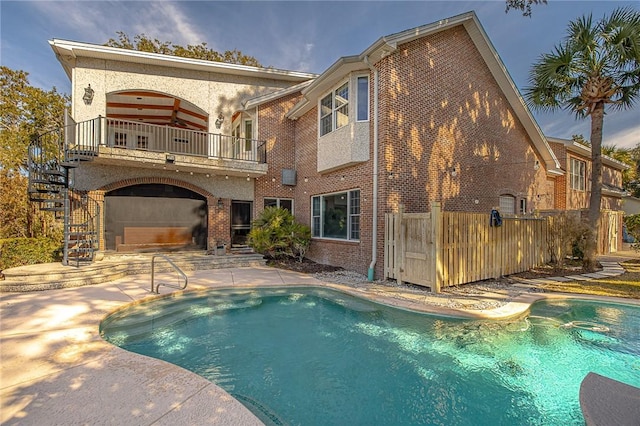 rear view of house with a balcony, a fenced in pool, and a patio area