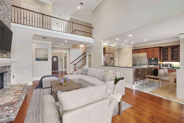 living room with crown molding, light hardwood / wood-style flooring, and a high ceiling