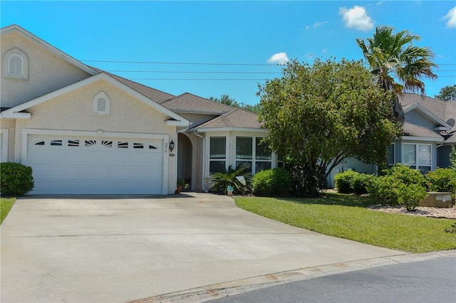 view of front of house featuring an attached garage, a front lawn, stucco siding, and driveway