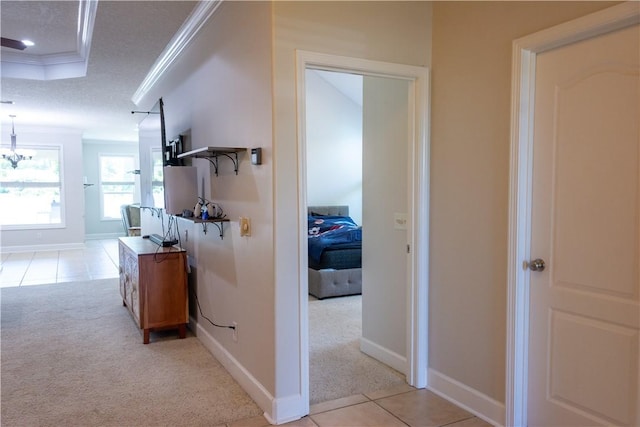 hallway with crown molding, baseboards, light tile patterned floors, and light carpet
