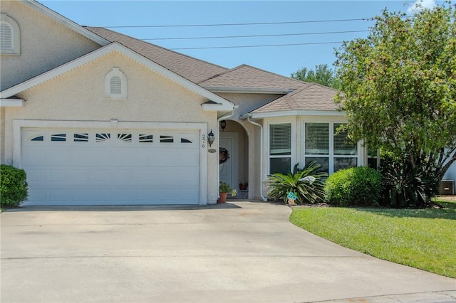 view of front of house with an attached garage, driveway, a shingled roof, and stucco siding