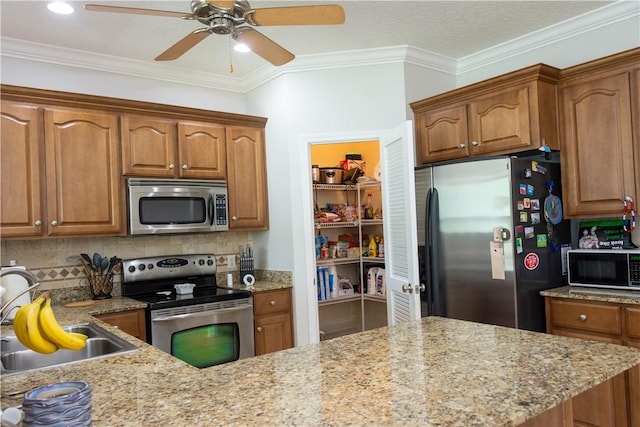 kitchen with crown molding, ceiling fan, brown cabinets, a sink, and appliances with stainless steel finishes