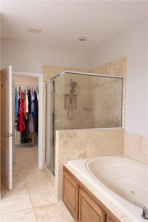 full bath featuring a tub with jets, a spacious closet, a shower stall, and tile patterned floors