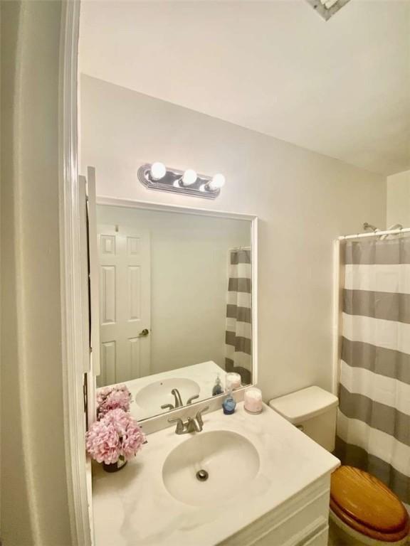 bathroom with a shower with shower curtain, toilet, and vanity