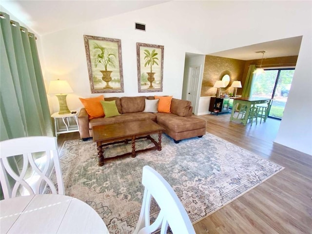 living room with lofted ceiling, visible vents, and wood finished floors