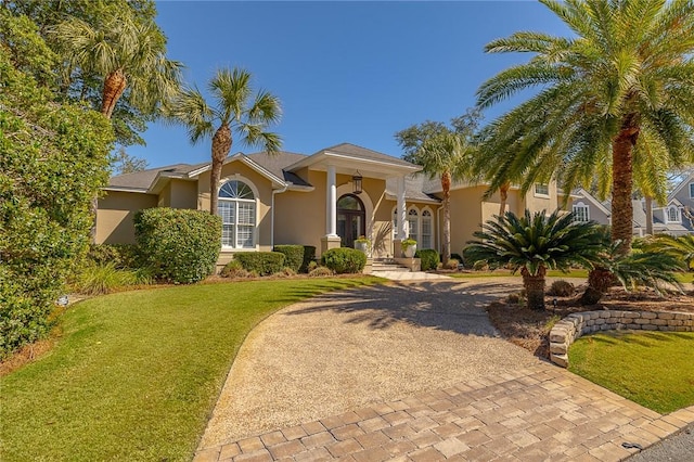 view of front of home featuring decorative driveway, a front yard, and stucco siding