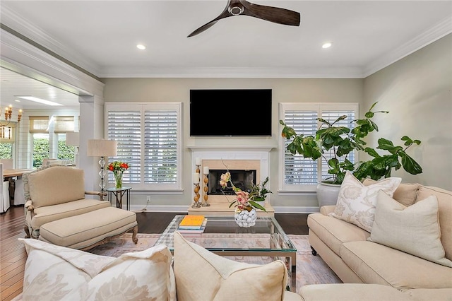 living area with ornamental molding, wood finished floors, a high end fireplace, and baseboards