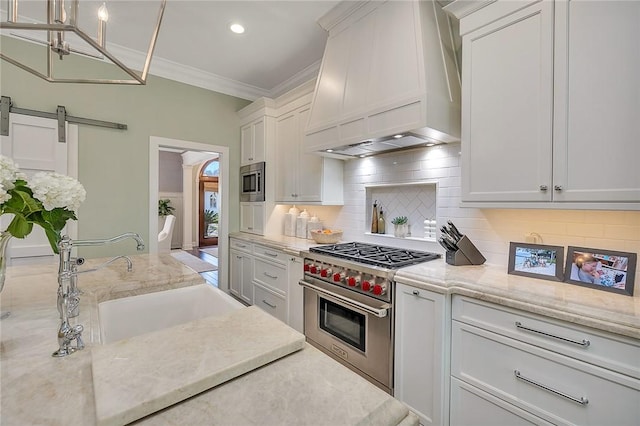 kitchen featuring stainless steel appliances, custom range hood, a barn door, ornamental molding, and a sink