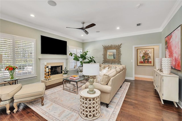 living room featuring dark wood-style flooring, a ceiling fan, a high end fireplace, ornamental molding, and baseboards