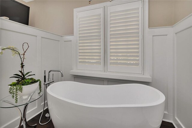 full bath featuring a decorative wall and a freestanding bath