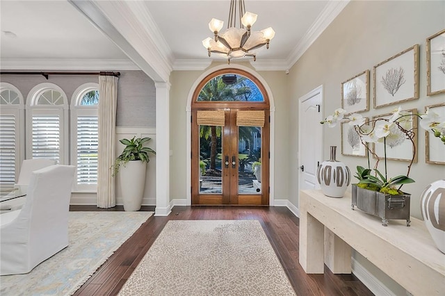 foyer entrance featuring dark wood-style floors, crown molding, baseboards, and an inviting chandelier