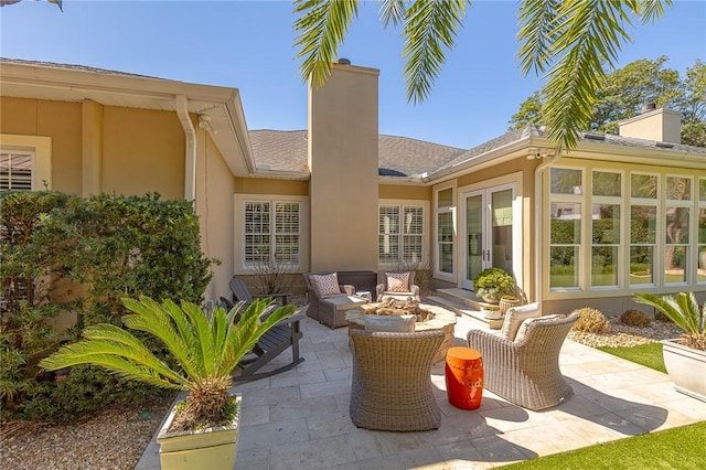 back of house with a chimney, a patio area, an outdoor living space, and stucco siding