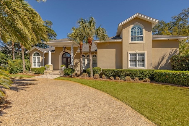 mediterranean / spanish house featuring a front lawn, french doors, and stucco siding