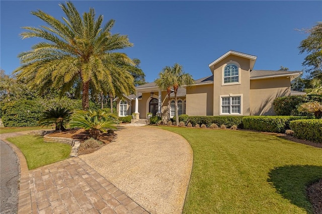 mediterranean / spanish house featuring driveway, a front lawn, and stucco siding