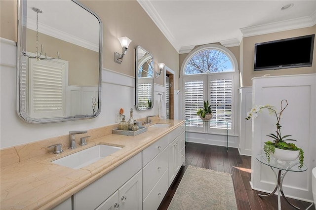 bathroom featuring a wealth of natural light, crown molding, a sink, and wood finished floors