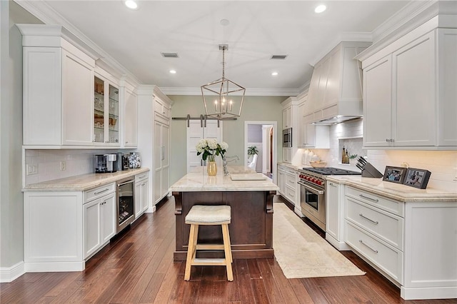 kitchen with a barn door, a kitchen island, wine cooler, custom exhaust hood, and stainless steel appliances