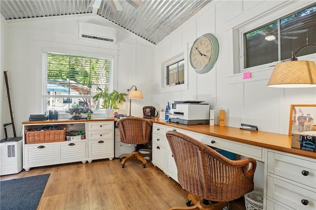 office space featuring a wall unit AC, lofted ceiling, and light wood-style floors