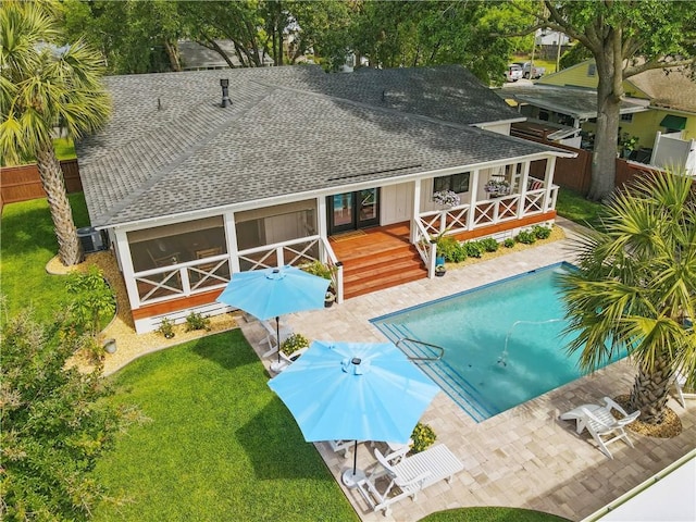 rear view of property with a fenced in pool, a deck, a shingled roof, fence, and a yard
