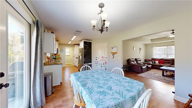 dining room featuring ceiling fan with notable chandelier, baseboards, and light wood-style floors