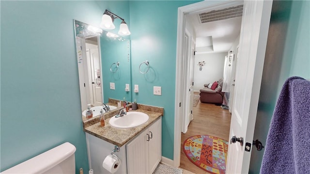 bathroom featuring vanity, wood finished floors, visible vents, baseboards, and toilet