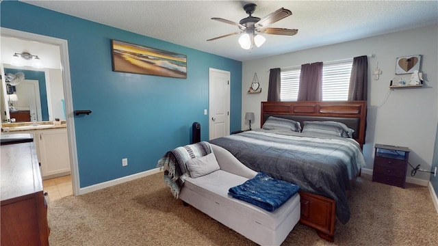 bedroom with baseboards, light carpet, ensuite bathroom, a textured ceiling, and a ceiling fan