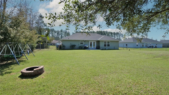 view of yard with french doors, a fire pit, a fenced backyard, and a playground