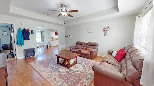 living room featuring visible vents, a raised ceiling, and light wood finished floors