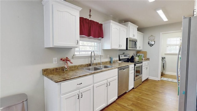 kitchen featuring a sink, stainless steel appliances, washer / clothes dryer, and white cabinetry