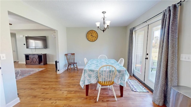 dining space featuring an inviting chandelier, french doors, baseboards, and light wood finished floors