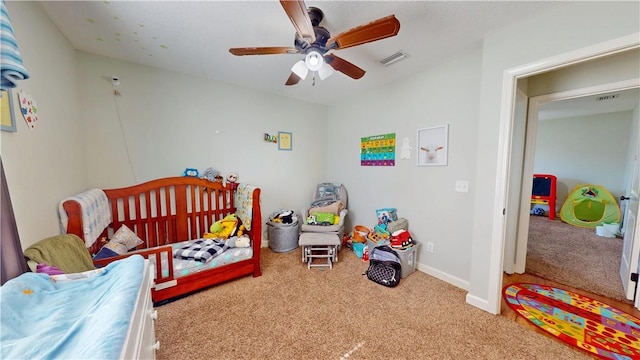 carpeted bedroom with visible vents, baseboards, and ceiling fan