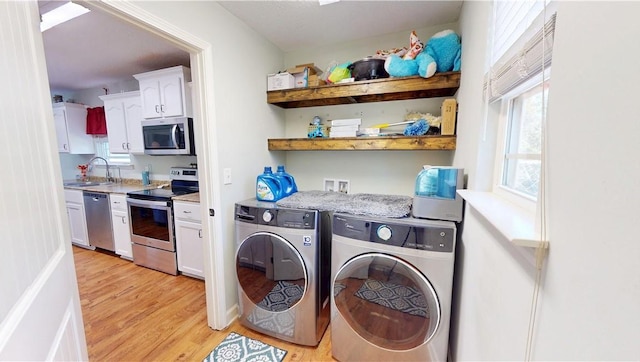 laundry room featuring a sink, light wood-style floors, and independent washer and dryer