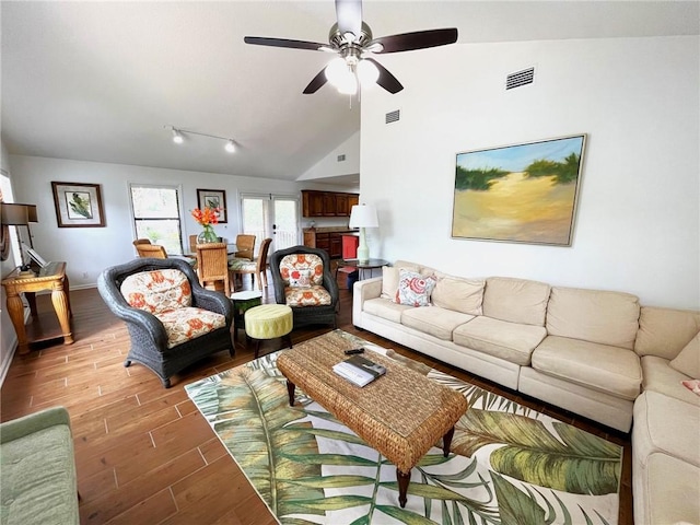 living room with light wood-type flooring, vaulted ceiling, and ceiling fan