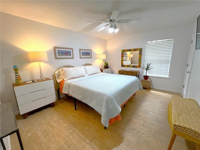 bedroom featuring a textured ceiling, light wood-type flooring, and ceiling fan