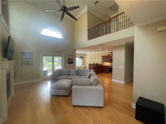 125 Palmera Ln, Brunswick, GA 31525 - living room featuring light wood-type flooring, crown molding, a ceiling fan, baseboards, and a towering ceiling