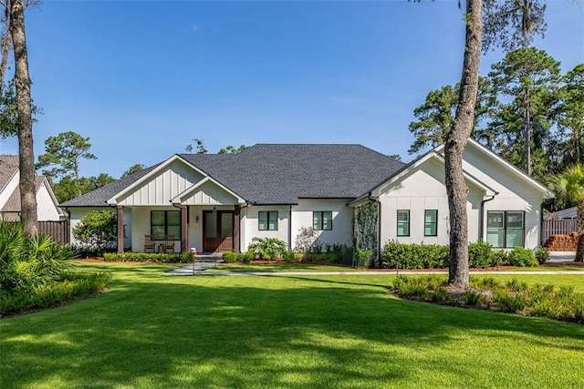 147 Butler Lake Dr, Saint Simons Island, GA 31522 - modern farmhouse featuring a front lawn, stucco siding, and a shingled roof