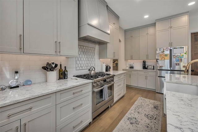 147 Butler Lake Dr, Saint Simons Island, GA 31522 - kitchen with stainless steel appliances, custom exhaust hood, recessed lighting, tasteful backsplash, and light wood-style flooring