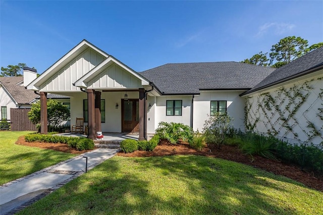147 Butler Lake Dr, Saint Simons Island, GA 31522 - view of front of house with covered porch, roof with shingles, a front lawn, and board and batten siding