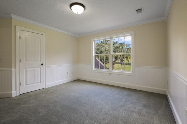 unfurnished room with ornamental molding, a textured ceiling, and dark colored carpet