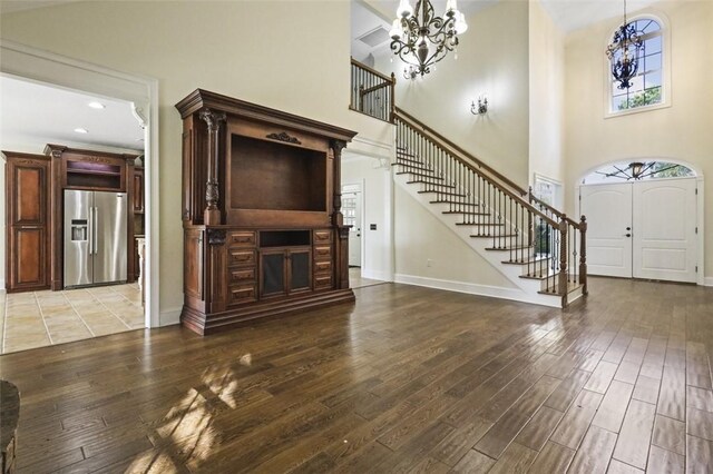 unfurnished living room featuring hardwood / wood-style floors, a high ceiling, and an inviting chandelier